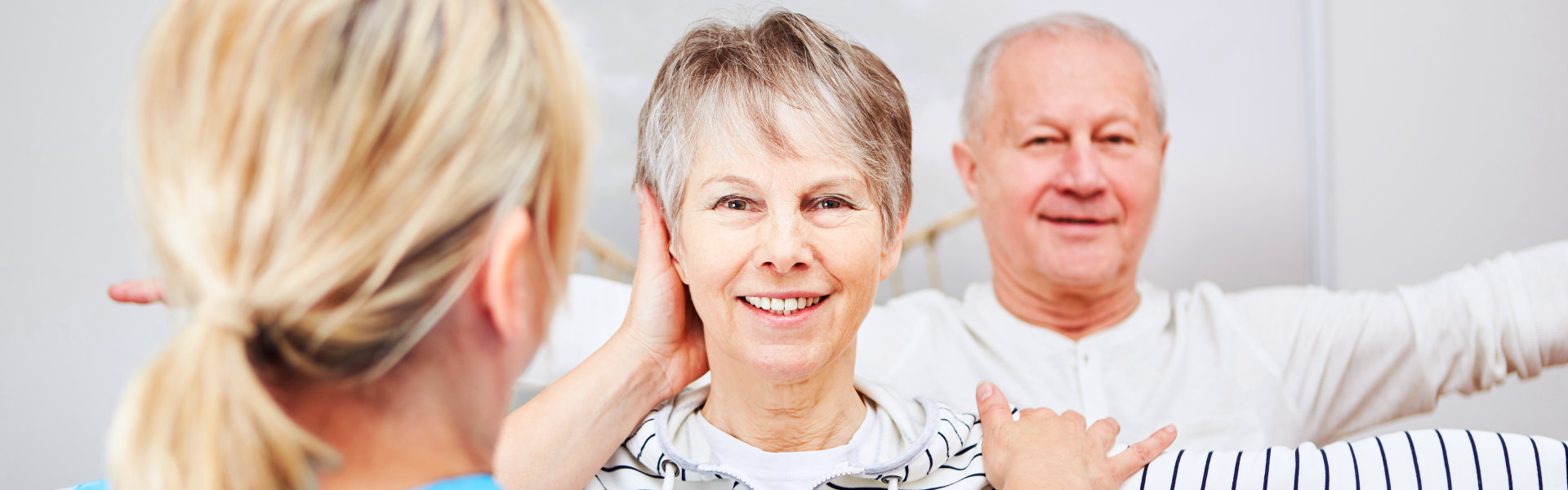 aide helping elderly couple do light exercise