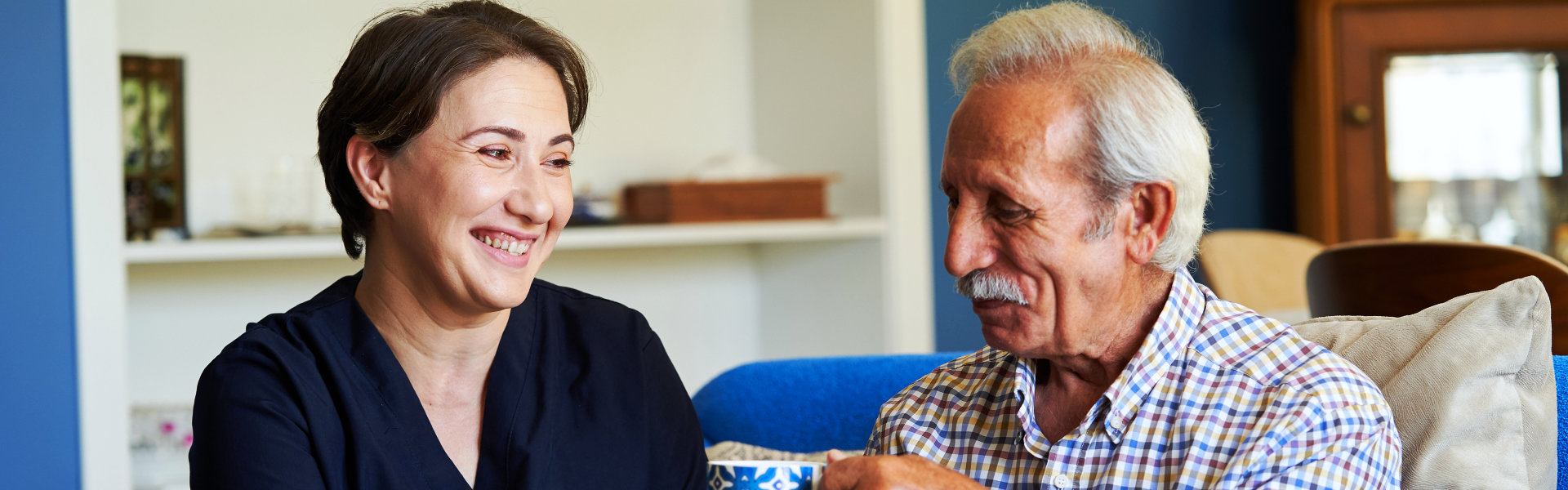 aide giving tea to an elderly man