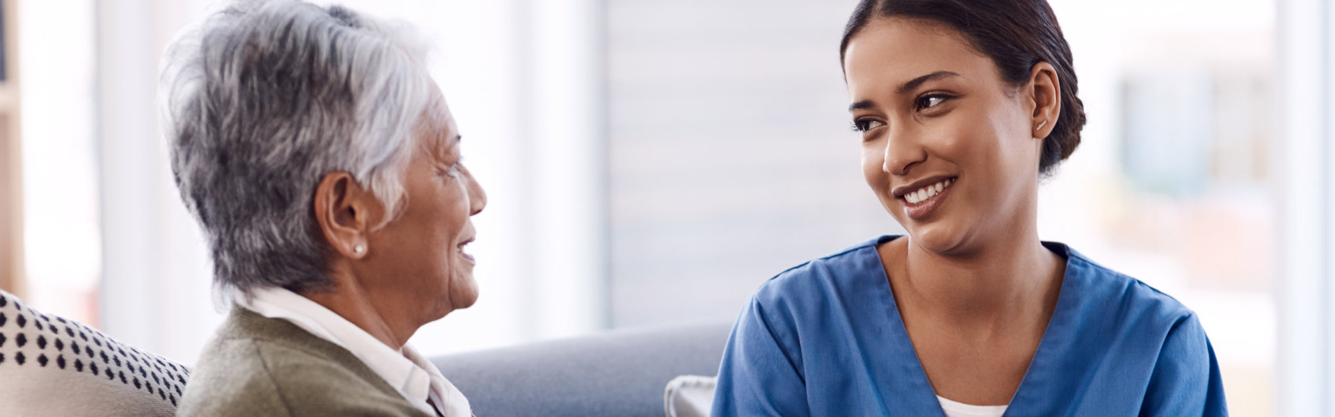 elderly woman and aide smiling at each other